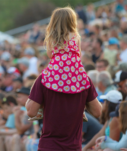 A little girl gets a ride on her dad's shoulders.