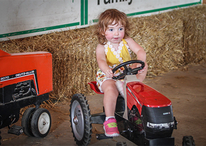 A little girl riding a toy tractor